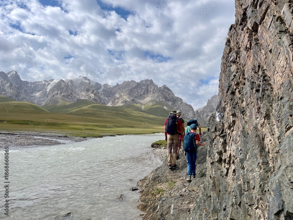 Fototapeta premium Family hiking in the scenic Key-Suu Valley, surrounded by mountains, alpine meadows, and natural landscapes, enjoying outdoor adventure. Kyrgyzstan.