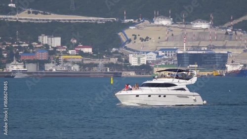 August 12, 2025: White motorboat near the port of Novorossiysk, Russia, with people relaxing on board