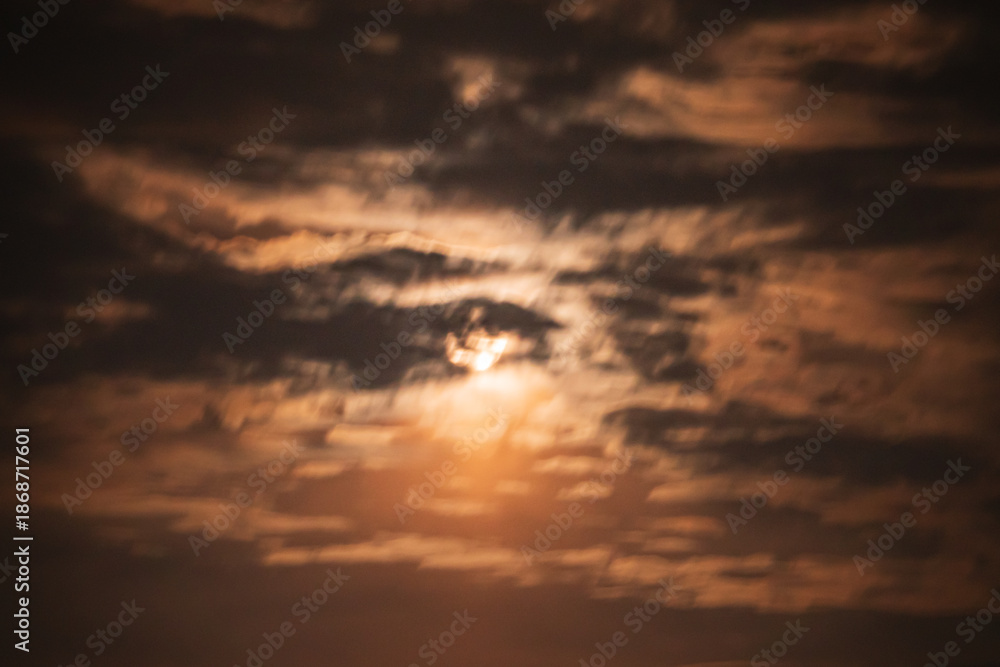 Obraz premium Moonlight filters through dark clouds at twilight, creating a mystical scene