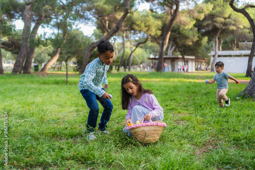 Children collecting colorful eggs in a basket during an outdoor easter egg hunt