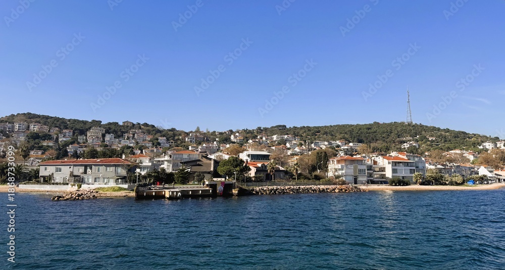 Obraz premium coastal town skyline seen from sea, rows of colorful houses clinging to hillside, waterfront pier and small harbor, calm blue