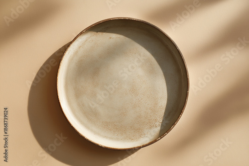 Minimal ceramic plate on beige textured background with soft natural shadows
