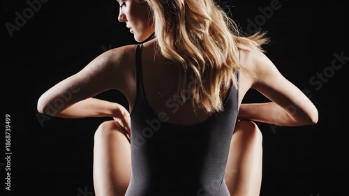 Woman in dark bodysuit with flowing hair against black background
