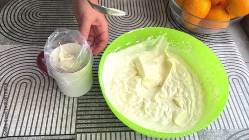 Hand filling piping bag with mascarpone cream. 4K horizontal footage shows a female hand transferring smooth dessert cream into a pastry bag for baking or decoration.