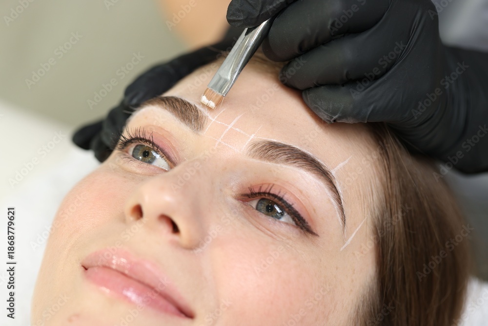 Naklejka premium Beautician drawing marks on woman's face before permanent eyebrow makeup procedure indoors, closeup