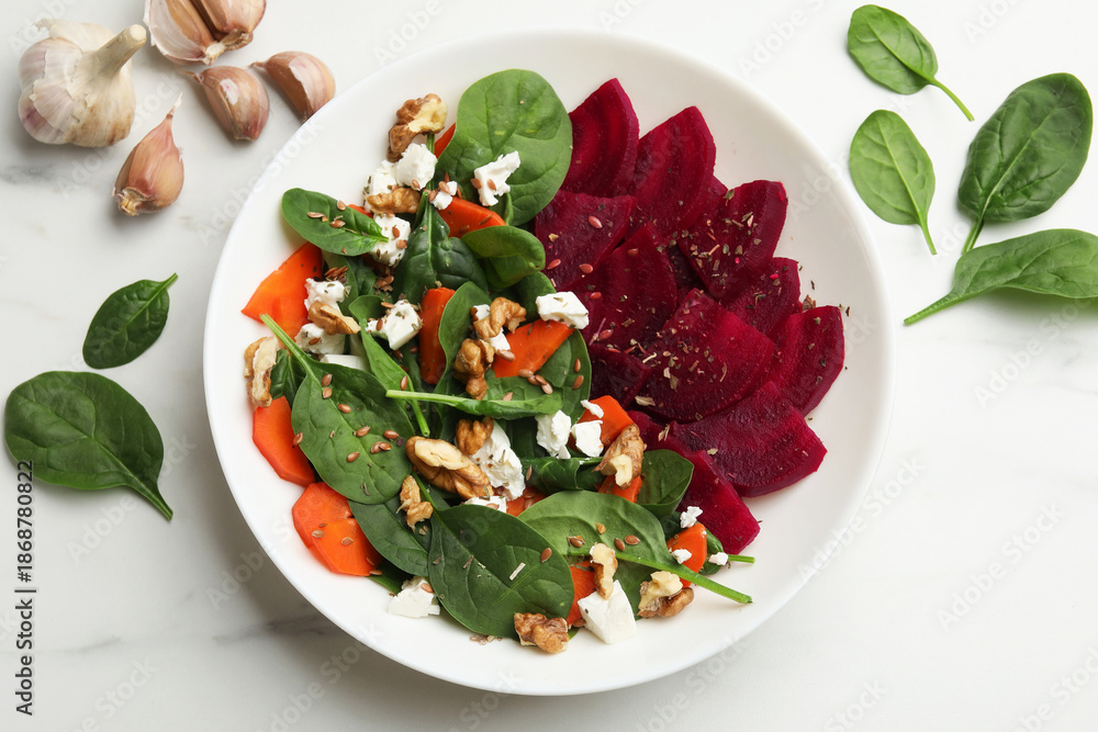 Obraz premium Delicious salad with beetroot, spinach, cheese, walnuts and carrot on white table, top view
