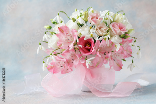 Spring delicate pink and white bouquet with lisianthus, eustoma, alstroemeria, snowdrops and a ribbon bow on a colorful background. Beautiful card