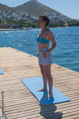 Enjoying a morning of yoga on the dock by the sea at a resort before sunset in a summer setting