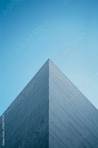Tall Building Reaches Sky With Glass Facade and Angle View Under Clear Blue Sky