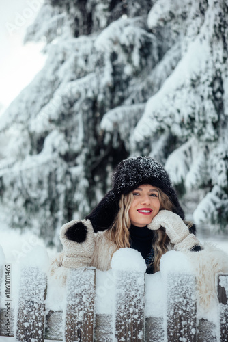 Woman smiling in winter scene with snow on trees and fence at mountain location