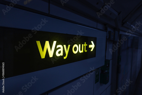 Way out sign glowing in dark underground station corridor