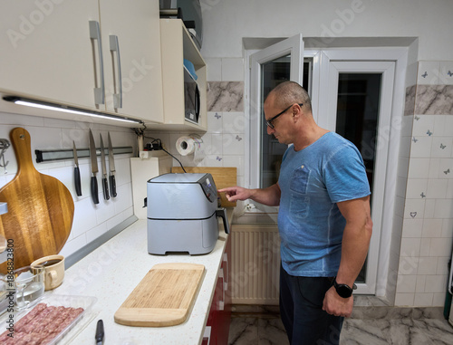Man setting airfryer in kitchen