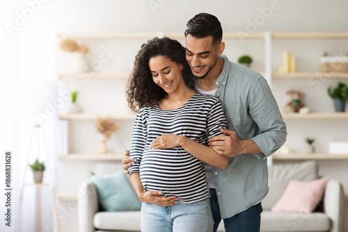 Wallpaper Mural Loving middle-eastern young man husband hugging his beautiful pregnant wife big tummy, millennial arabic family waiting for baby, home interior, copy space. Family, childbirth, pregnancy concept Torontodigital.ca