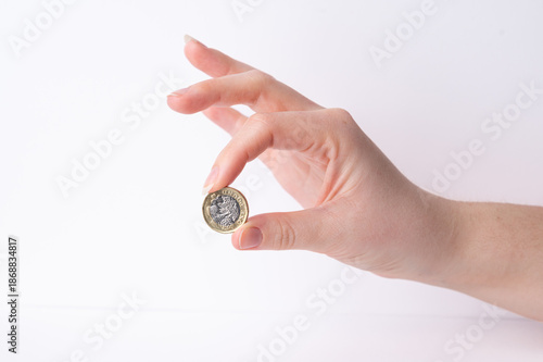 Hand holding a one pound coin against a white background