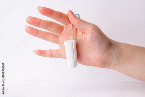 Hand holding a tampon with white background in a bathroom setting