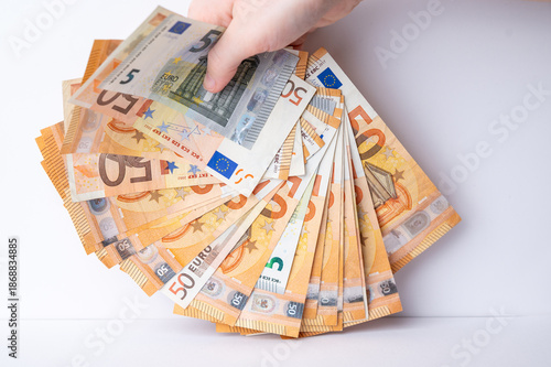 Hand holding a fan of euro banknotes in a bright space