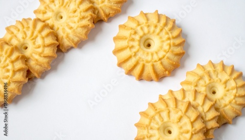 Wheel-shaped golden cookies arranged on white background, showcasing geometric consistency and baked texture.