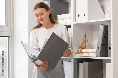 Female secretary searching for document in folder at office