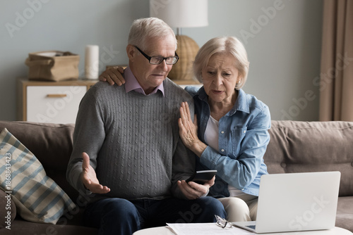 Pension planning challenges. Confused aged spouses retirees review monthly expenses at home office check calculator with stressed look facing debt financial problem after unexpected high utility bill