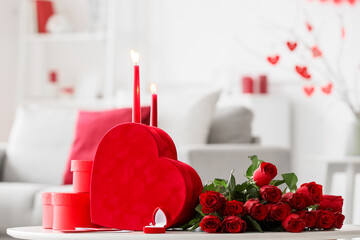 Gifts for Valentine's Day with roses, engagement ring and burning candles on table in living room