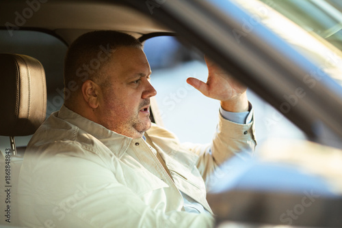 Mature man gesturing angrily while driving in car