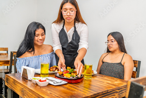 Waitress serving fusion food to female customers