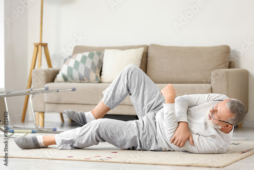 Photos Senior man with walker lying on floor after fall at home