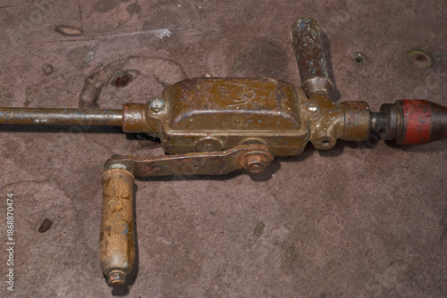 Vintage metal hand drill with wooden elements and visible wear. Traditional manual drilling tool representing craftsmanship, repair work, and historical technology.