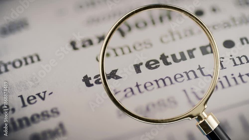 magnifying glass hovering over paper article that says tax return, paying taxes