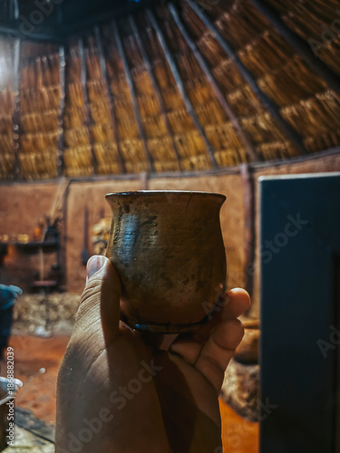 POV photo of a hand holding a jar of cocoa drink, in a very minimalist style, with a completely traditional southern Mexican kitchen in the background
