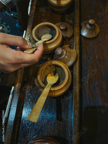 Hand taking a spoon from a bowl with brown sugar and other spices to prepare cocoa drink.
