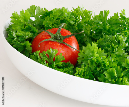 Fresh Tomato in Bowl of Green Parsley on White Background