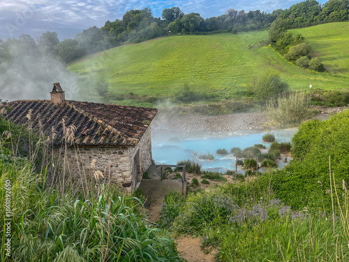 Old stone mill house by the turquoise thermal springs of Saturnia with steam in Tuscany, Italy.