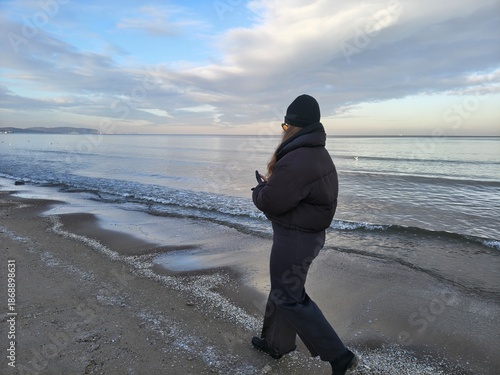 Kobieta spacerujaca brzegiem morza