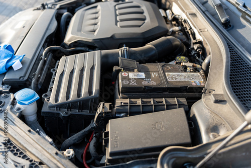 Close-up view of car engine compartment with EFB battery air filter box washer fluid reservoir and motor cover under open hood. Automotive maintenance, vehicle inspection and car repair service.