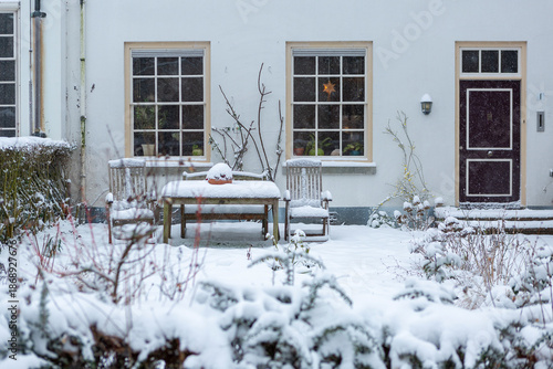 White exterior facade of monumental cultural heritage building with wooden bench at the entrance and snow from after blizzard snowstorm on the pavement in front