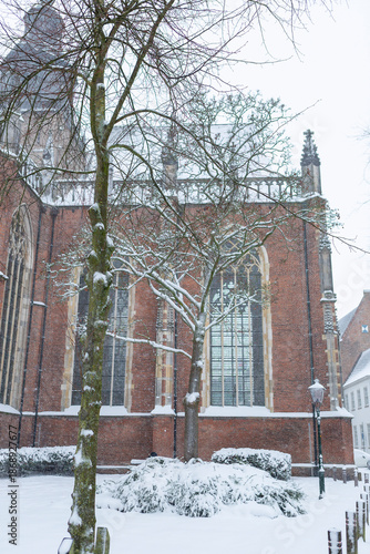 Detail of Walburgis church in historic Dutch city center with snow on the roof and in the street below