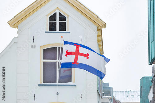 Zutphen regional city flag waving in the wind with exterior facades of city centre buildings with large window panes behind