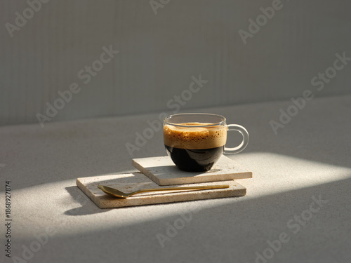 A glass cup of rich espresso with a golden spoon