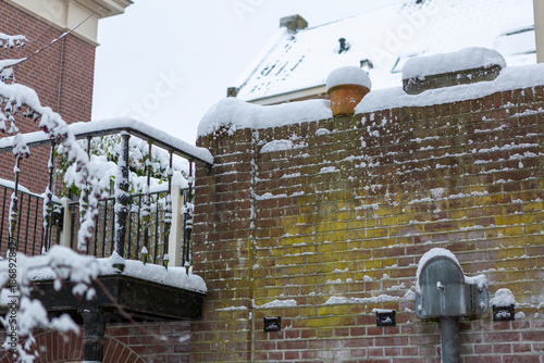 Stone statues marking the entrance of a courtyard in the city center of historic medieval town covered in snow. Winter wonderland urban scene