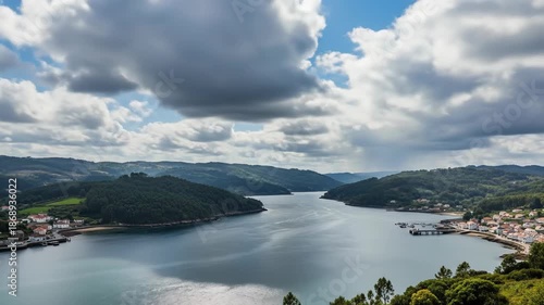 Scenic view of a large river surrounded by lush green hills under cloudy sky.