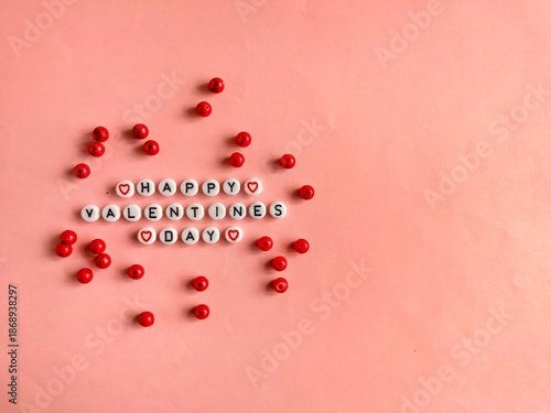 happy valentine’s day text made of letter beads with red bead decoration on pink background
