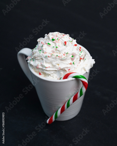 Chocolat chaud festif à la menthe avec chantilly et canne de bonbon sur fond noir