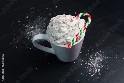 Chocolat chaud festif à la menthe avec chantilly et canne de bonbon sur fond noir
