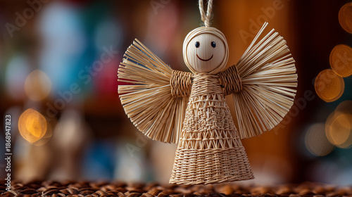Orthodox Christmas handmade toy, close-up of small straw angel ornament, warm home interior blurred behind