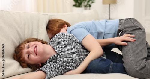 Two brothers fooling around on sofa at home