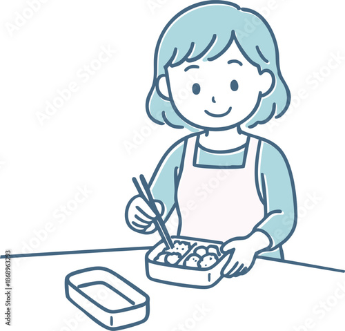 お弁当を詰めるエプロン姿の女性