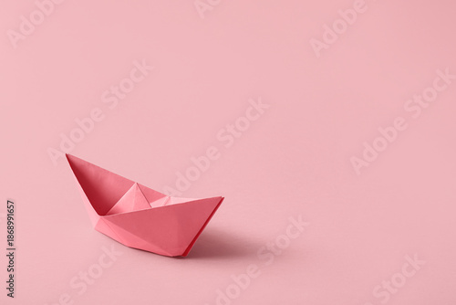 Pink paper boat on color ba...