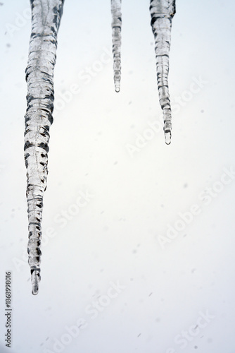 Close-up of long transparent icicles hanging from a roof in winter