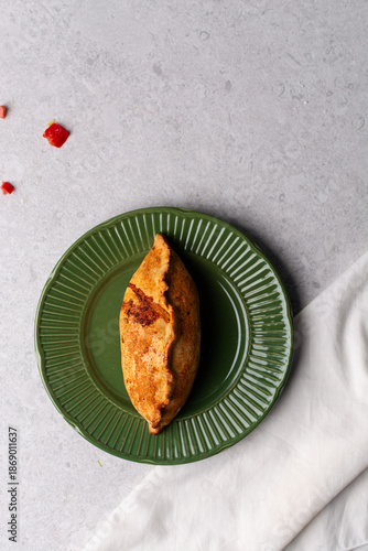Quadro em tela Overhead view of baked empanadas with pico de gallo on a green plate, top view o